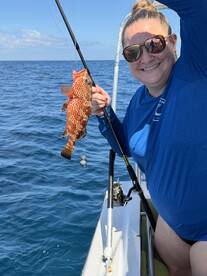 A joyful angler proudly displays her catch while fishing on the open ocean, showcasing the excitement of a day on the water.
