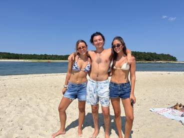 A cheerful group of friends poses together on the beach, enjoying a sunny summer day — perfect for beach outings and memorable moments.