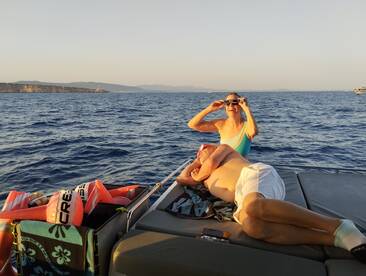 A joyful couple enjoys their time on a boat, capturing the moment with smiles and laughter against a beautiful ocean backdrop.