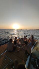 A lively group enjoys a stunning sunset aboard a yacht, creating unforgettable memories during their ocean adventure.