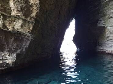 A stunning view of a natural cave opening, revealing bright light and tranquil waters — a perfect representation of coastal exploration.