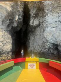 A vibrant boat navigates through a rocky cave, showcasing the stunning natural formations and the adventure of exploring hidden waterways.