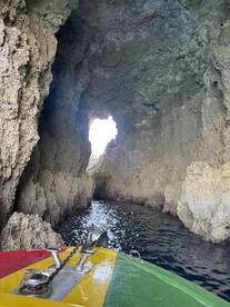 A vibrant boat approaches a stunning cave entrance, showcasing the natural beauty of the coastline — perfect for adventure seekers exploring hidden gems.