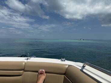 A serene view from the deck of a boat, showcasing calm ocean waters and a distant vessel — perfect for a relaxing day on the water.