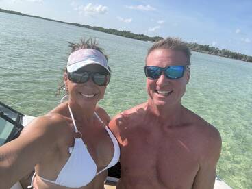 A cheerful couple takes a selfie on a sunny day by the water, showcasing their fun boating adventure.