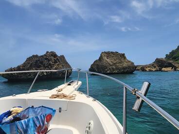 A scenic view from the bow of a boat navigating through clear waters, showcasing unique rock formations in the distance — perfect for exploring coastal landscapes.