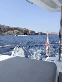 A scenic view from the deck of a boat cruising past stunning coastal cliffs, showcasing the beauty of the open sea.
