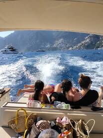 A group of friends and family relax on the back of a boat, enjoying the stunning coastal scenery — a perfect day on the water.