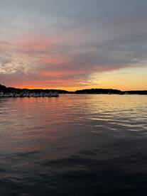A stunning sunset casts vibrant colors over the harbor, creating a picturesque scene perfect for evening boat outings.