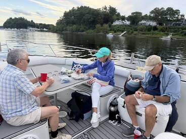 A group of friends enjoys snacks and drinks on a boat, creating a perfect atmosphere for relaxation and socializing on the water.