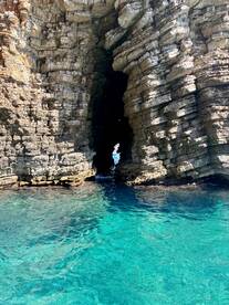A stunning view of a natural rock formation with a clear passageway, surrounded by turquoise waters — a perfect spot for exploration and scenic boat trips.