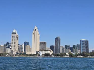 A stunning view of the San Diego skyline from the water, showcasing the vibrant cityscape and a sailboat in the foreground — perfect for capturing the essence of coastal adventures.