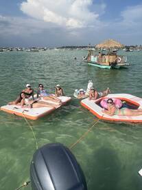 A lively group of friends enjoys a fun day on floating mats in the water, perfect for summer parties and relaxation.