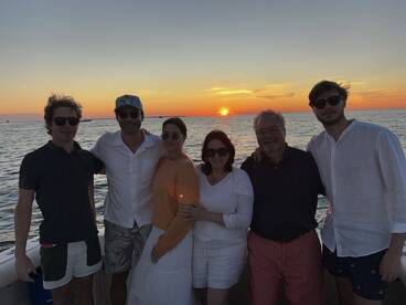 A cheerful group poses for a photo on a boat at sunset, capturing a memorable moment during their maritime adventure.