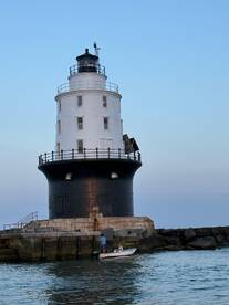 A small boat approaches a historic lighthouse, with people onboard enjoying the scenic view — a perfect moment for maritime exploration.