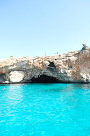 A stunning view of a natural cave with swimmers enjoying the vibrant turquoise waters — a perfect spot for adventure and exploration.
