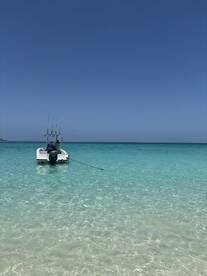 A speedboat anchored in crystal-clear waters, showcasing a serene day on the water — perfect for fishing or leisure activities.