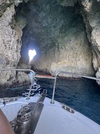 A stunning view from the bow of a boat as it navigates through a rocky cave, showcasing the beautiful coastal scenery — perfect for adventure seekers exploring hidden gems.