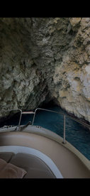 A serene view from inside a boat as it navigates through a stunning cave, showcasing the beautiful rock formations and clear blue water.
