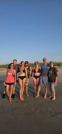 A lively group of friends enjoys a beach day, celebrating together with drinks and smiles — perfect for memorable summer outings.