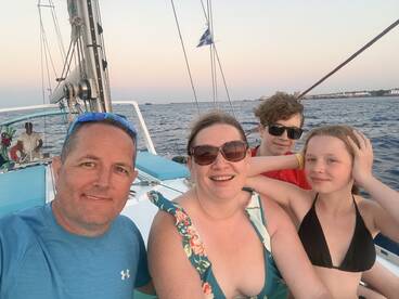 A joyful family captures a moment aboard a sailboat during sunset, creating lasting memories on the water.