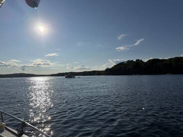 A serene view of boats on the water under a bright sun, capturing the beauty of a perfect day on the lake.