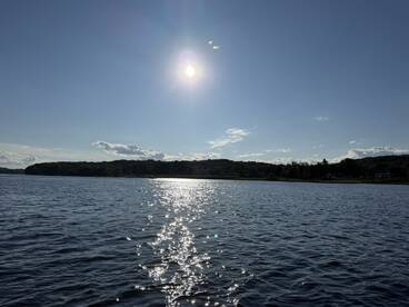 A serene view of the sun reflecting on the water, capturing the beauty of a tranquil sunset — perfect for nature lovers and boating enthusiasts.