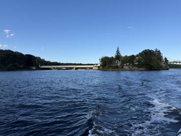 A picturesque view of a serene waterway featuring an island and a bridge, perfect for capturing the beauty of nature during a boating trip.