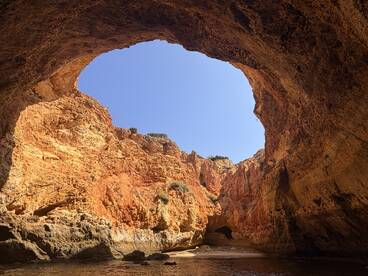 A stunning view of a natural cave formation, showcasing vibrant rock colors and clear blue skies — a perfect destination for scenic boat tours.
