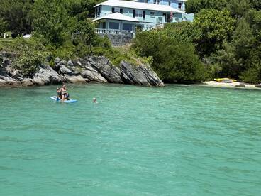 A fun day on the water with a group paddleboarding and swimming in the clear turquoise waters, perfect for family adventures and beach outings.