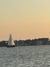 A serene view of a sailboat gliding across the water at sunset, showcasing the beauty of sailing and tranquil waterside scenery.