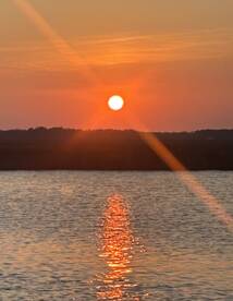 A stunning sunset casts a warm glow over the water, creating a beautiful reflection — perfect for capturing serene moments on the water.