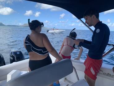 A group prepares for snorkeling off the side of a boat, showcasing the excitement of ocean adventures and water activities.