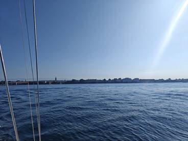 A serene view of the water with a distant shoreline, showcasing a peaceful boating experience under clear skies.