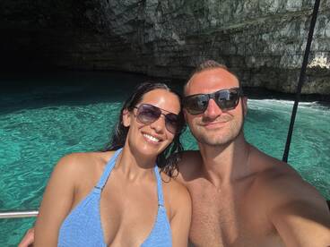 A couple enjoys a sunny day on the water, capturing a selfie against a stunning cave backdrop — perfect for romantic adventures and scenic explorations.