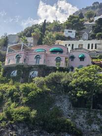 A picturesque view of a colorful villa perched on a hillside, surrounded by lush greenery and scenic landscapes.