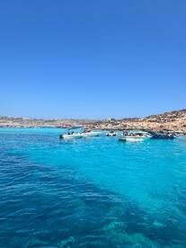A vibrant scene showcasing multiple boats anchored in crystal-clear turquoise waters along a picturesque coastline, perfect for a day of exploration and adventure.