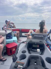 A lively group enjoys drinks aboard a pontoon boat, capturing the essence of a fun day on the water with friends.