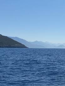 A stunning view of a serene coastline with distant mountains, capturing the beauty of the open water and perfect for nature lovers and adventure seekers.