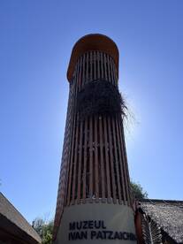A tall structure with a unique design, possibly a museum, set against a clear blue sky.
