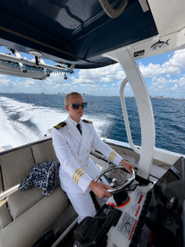 A young captain navigates the helm of a boat, showcasing the modern console and a stylish interior — perfect for those aspiring to take the helm on their next adventure.