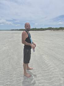 A man stands on a sandy beach, enjoying the outdoors under a clear sky — a perfect moment for beach lovers and adventure seekers.