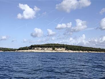 A picturesque view of a lush coastline and island, showcasing the natural beauty of the area — perfect for exploring by boat.