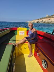 A woman relaxes inside a colorful boat, showcasing the vibrant seating area and inviting atmosphere for a day on the water.
