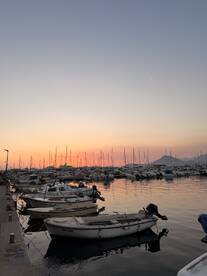 A serene sunset view over a marina filled with various boats, creating a picturesque scene perfect for evening strolls or boating adventures.