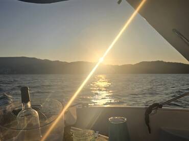 A serene sunset view from a boat, featuring a wine bottle and glass, creating a perfect ambiance for a relaxing evening on the water.