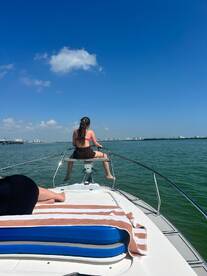 A young girl enjoys the sun while sitting at the bow of a boat, taking in the beautiful water views on a sunny day — perfect for a relaxing day on the water.
