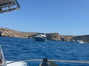 A stunning view of multiple yachts anchored near a rocky coastline, showcasing the beauty of maritime adventures.