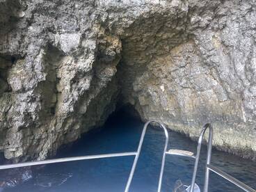 A stunning view of a cave entrance from a boat, showcasing the beautiful blue waters and rocky formations — perfect for exploring hidden gems during your aquatic adventures.