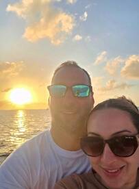 A couple enjoys a romantic sunset selfie on the water, capturing a perfect moment of celebration and togetherness.